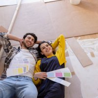 happy couple day dreaming with color swatches lying on floor in new living room - home decoration stock pictures, royalty-free photos & images