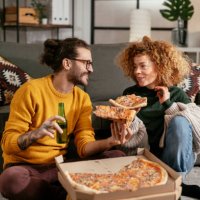 happy couple drinking beer and eating pizza, spending time together at home stock photo - junk food stock pictures, royalty-free photos & images