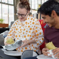 happy couple eating burritos at home - junk food stock pictures, royalty-free photos & images