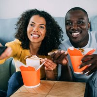 happy couple eating chinese food and watching tv at home. - junk food stock pictures, royalty-free photos & images
