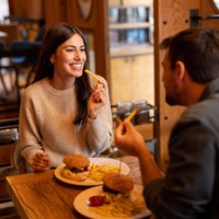 happy couple eating in the restaurant - junk food stock pictures, royalty-free photos & images