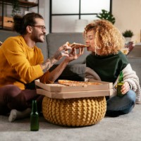 happy couple eating pizza at home. stock photo - junk food stock pictures, royalty-free photos & images