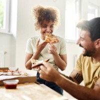 happy couple eating pizza at their new apartment. - junk food stock pictures, royalty-free photos & images
