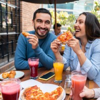 happy couple eating pizza with a group of friends - food stock pictures, royalty-free photos & images