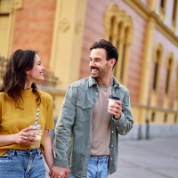 happy couple holding hands and drinking coffee while walking down the street - junk food stock pictures, royalty-free photos & images