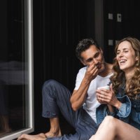 happy couple in nightwear at home sitting at french window - coffee stockfoto's en -beelden