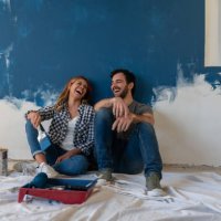 happy couple laughing while taking a break from painting - home decoration stock pictures, royalty-free photos & images