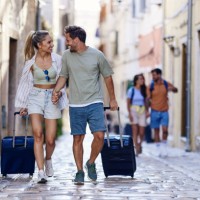 happy couple of tourists dragging their suitcases on the street. - travel stock pictures, royalty-free photos & images