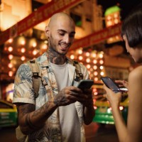 happy couple of tourists using smart phone on the city street at night. - fashion stock pictures, royalty-free photos & images