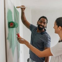 happy couple painting together with smiles - home decoration stock pictures, royalty-free photos & images