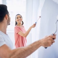 happy couple painting wall in apartment together - home decoration stock pictures, royalty-free photos & images