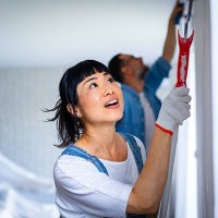 happy couple renovating their home, painting the wall and smiling while working together - home decoration stock pictures, royalty-free photos & images