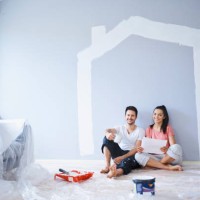 happy couple taking break from painting walls in new apartment - home decoration fotografías e imágenes de stock