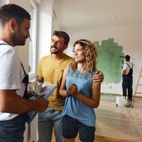 happy couple talking to their house painter inside of renovating apartment. - home decoration stock pictures, royalty-free photos & images