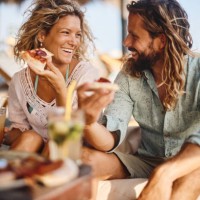 happy couple talking while eating pizza in a beach bar. - home decoration stock pictures, royalty-free photos & images