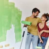happy couple talking while painting their new apartment. - home decoration stock pictures, royalty-free photos & images