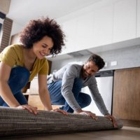 happy couple unrolling a carpet at home - home decoration stock pictures, royalty-free photos & images