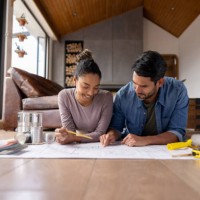 happy couple working on a home addition project and sketching some blueprints - home decoration stock pictures, royalty-free photos & images