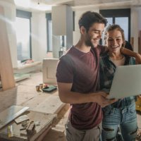 happy embraced couple using laptop while being on construction site in their apartment. - home decoration stock pictures, royalty-free photos & images