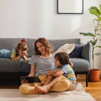happy family moments: the mother sits on the floor and watches something on the digital tablet with her kids - home decoration stock pictures, royalty-free photos & images