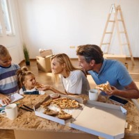 happy family talking while eating pizza after unpacking their belongings in new home. - junk food stock pictures, royalty-free photos & images