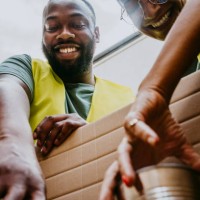 happy female and male heroes arranging canned foods in box - food stock pictures, royalty-free photos & images
