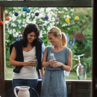 happy female friends holding drink bottles while standing in log cabin during party - garden decoration stock pictures, royalty-free photos & images