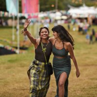happy female friends walking with arms around at park - concert stock pictures, royalty-free photos & images