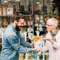 happy florist giving a flower bouquet to a smiling young man - garden decoration stock pictures, royalty-free photos & images