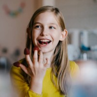 happy girl sitting at kitchen table at home playing with raspberries - food stock pictures, royalty-free photos & images