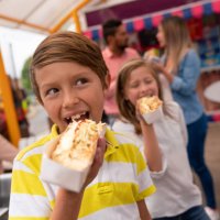 happy kids eating junk food at an amusement park - food stock pictures, royalty-free photos & images