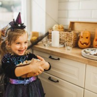 happy laughing baby girl with bowl of popcorn on kitchen, decorated for halloween - home decoration stock pictures, royalty-free photos & images
