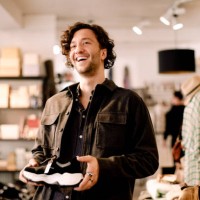 happy male customer looking away while buying shoe at retail store - fashion stock pictures, royalty-free photos & images