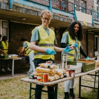 happy male volunteer giving canned food to female friend working in garden - food stock pictures, royalty-free photos & images