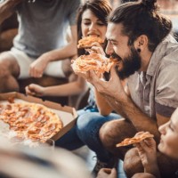 happy man eating pizza with his friends at home. - junk food stock pictures, royalty-free photos & images