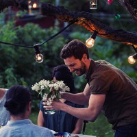 happy man holding flower vase while enjoying dinner party with friends at yard - garden decoration stock pictures, royalty-free photos & images