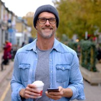 happy man outdoors using his cell phone while drinking a cup of coffee - junk food stock pictures, royalty-free photos & images