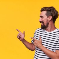 happy man pointing into a blank copy space spot with two hands. - hairstyle stock pictures, royalty-free photos & images