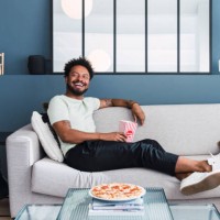 happy man spending leisure time sitting on sofa at home - junk food stock pictures, royalty-free photos & images