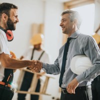 happy manual workers shaking hands with an architect at construction site. - home decoration stock pictures, royalty-free photos & images