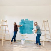happy mature couple talking while painting their new apartment. - home decoration stock pictures, royalty-free photos & images