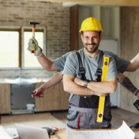 happy multi-tasking construction worker with crossed arms during renovation process. - home decoration stock pictures, royalty-free photos & images