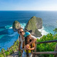 happy multiracial couple standing above kelingking beach, enjoying the view and taking selfies - travel stockfoto's en -beelden