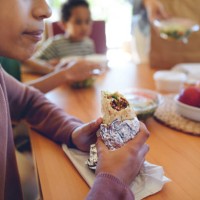 happy multiracial family sitting at dining table and having lunch at home. - junk food stock pictures, royalty-free photos & images