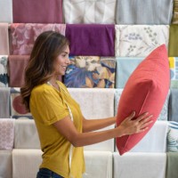 happy saleswoman working at a fabric shop and holding a cushion - home decoration stock pictures, royalty-free photos & images
