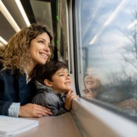 happy single mother and son looking at the window view both smiling while traveling by train - travel stock pictures, royalty-free photos & images