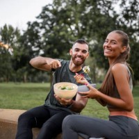 happy sporty couple eating vegetable salad after intensive workout - food stock pictures, royalty-free photos & images
