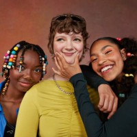 happy teenage female friends standing against brown background - fashion fotografías e imágenes de stock