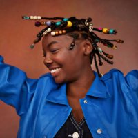 happy teenage girl wearing blue jacket shaking head against brown background - hairstyle stock pictures, royalty-free photos & images