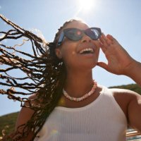 happy woman adjusting sunglasses on sunny day - hairstyle photos et images de collection